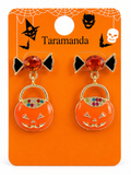 A pair of Halloween-themed stud earrings on an orange backing card. The earrings feature a black bow with a faceted orange-red top and a dangling orange pumpkin bucket charm with gold trim and multicolor rhinestones.