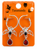 Silver-tone hoop earrings with bat and teardrop pendant charms, displayed on an orange Halloween-themed card labeled Taramanda.
