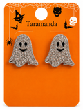 A pair of ghost-shaped stud earrings covered in silver rhinestones with black enamel eyes and mouths, displayed on an orange Halloween-themed card labeled Taramanda.