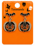 A pair of Halloween-themed dangle earrings on a branded orange display card. The earrings feature black bat charms above pumpkin-shaped drops with black enamel, gold-tone outlines, and rhinestone trim.