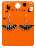 A pair of silver-tone bat drop earrings with black glitter centers, displayed on an orange Halloween-themed card labeled 'Taramanda'.