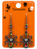 A pair of Halloween dangle earrings displayed on an orange retail backing card. The earrings have silver-toned spider charms with rhinestone-embellished centers and faceted iridescent beads above them.