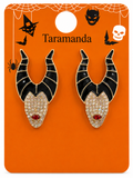 A pair of Maleficent-inspired stud earrings on a branded orange display card. The earrings have black horn shapes outlined in gold, a rhinestone-encrusted face, and a small red gem at the mouth.